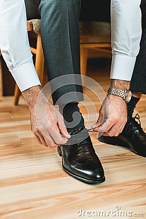 Man ties his shiney new black leather shoes Stock Photo