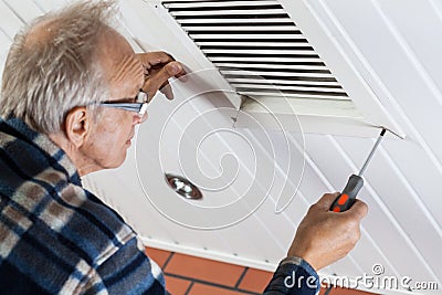 Man tightening the bolts on ventilation grille Stock Photo