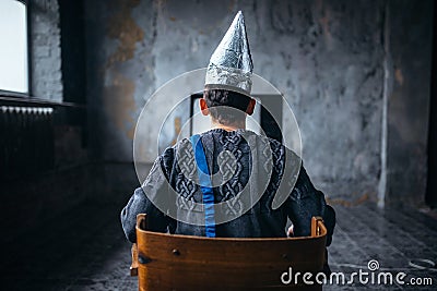 Man in tinfoil helmet watches TV, ufo phobia Stock Photo