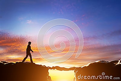 Man about to croos precipice between mountains over another man Stock Photo