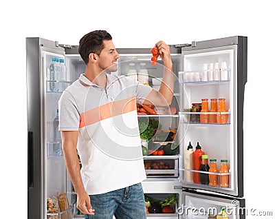 Man with tomatoes near open refrigerator on background Stock Photo