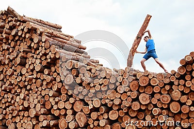 Man on top of large pile of logs lifting heavy log - training Stock Photo
