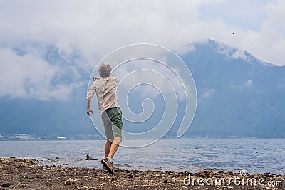 Man tourist at the lake Bratan and the mountains covered with cl Stock Photo