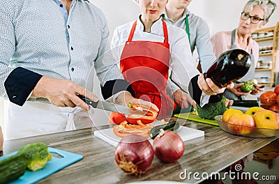 Man in training kitchen cutting vegetables under watchful eye of dietician Stock Photo