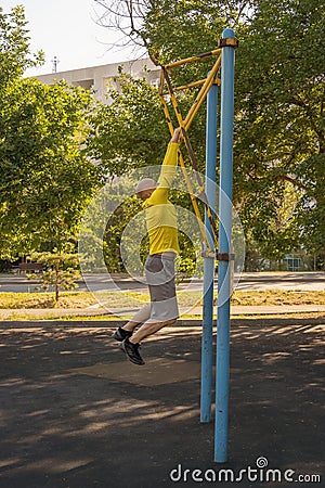 Man trains on a rock climbing machine on a street sports ground. Stock Photo