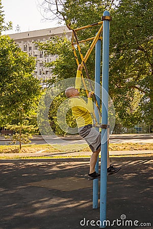 Man trains on a rock climbing machine on a street sports ground. Stock Photo