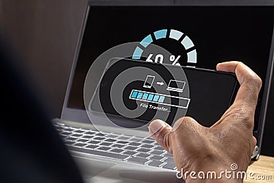Man transfer files from mobile phone to laptop. Backup, Copy file and media or exchange data concept Stock Photo