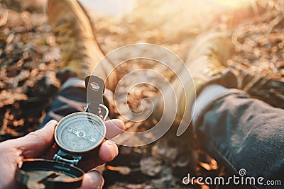 Man traveler hold compass in hand on background legs in hiking boots. Blurred background Stock Photo