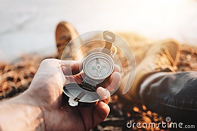 Man traveler hold compass in hand on background legs in hiking boots. Blurred background Stock Photo