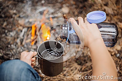 Man traveler pours water from a bottle into a metal mug. Stock Photo