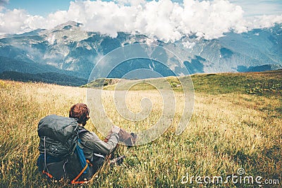 Man Traveler relaxing sitting on grass valley at mountains Stock Photo