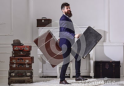 Man, traveller with beard and mustache with luggage, luxury white interior background. Macho elegant on cheerful face Stock Photo