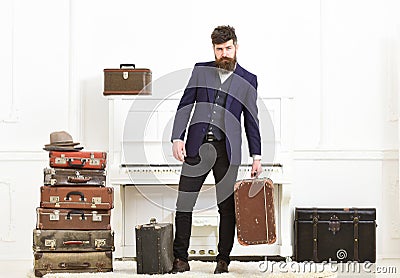 Man, traveller with beard and mustache with luggage, luxury white interior background. Macho elegant on strict face Stock Photo