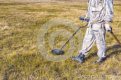 Man on a treasure hunt with a metal detector in the woods on the field Stock Photo