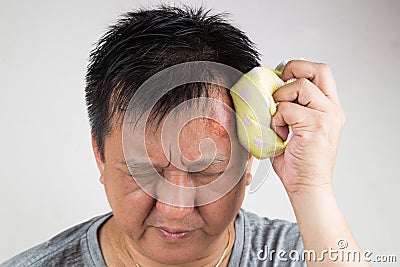 Man treating his injured painful swollen forehead bump with icepack Stock Photo