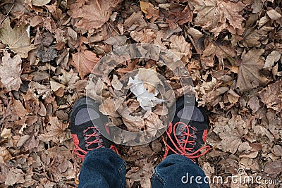 Man in trekking boots and jeans on the ground with dryed orange leaves Stock Photo