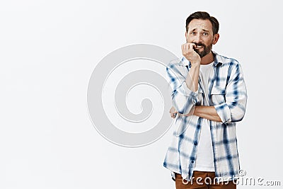 Man trying quiet smoking, biting fingernails while feeling need to smoke, frowning and gazing with sad expression aside Stock Photo