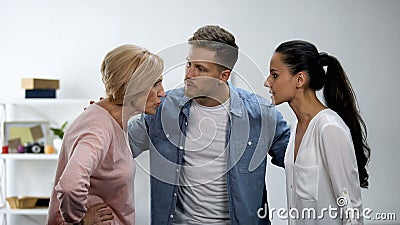 Man trying to calm wife and mother arguing, in-law conflict, troubled marriage Stock Photo