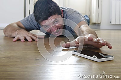 Man trying to reach mobile phone creeping on the ground in smart phone and internet addiction concept Stock Photo