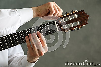 Man tunes classic guitar against dark background Stock Photo