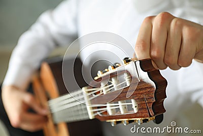 Man tunes classic guitar against dark background Stock Photo