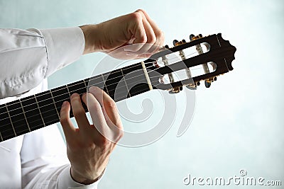 Man tunes classic guitar against light background Stock Photo