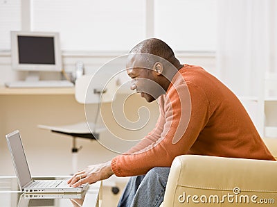 Man typing on laptop in livingroom Stock Photo