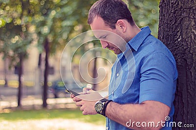Man typing on the phone in a park Stock Photo
