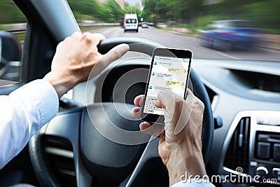 Man Typing Text Message On Mobile Phone While Driving Car Stock Photo