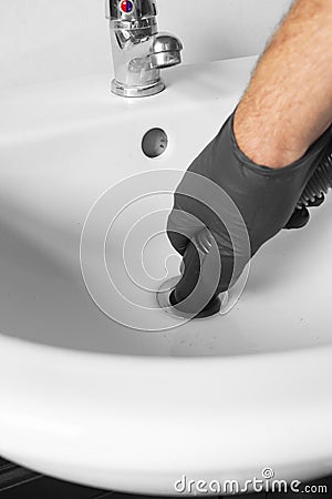 Man unblocking pipes in a bathroom sink using a hoover. Stock Photo
