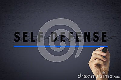 Man underlining words Self Defense with marker glass board against dark grey background, closeup Stock Photo