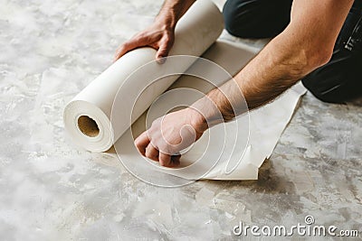 Man unraveling a rolled white wallpaper, illustrating home renovation and interior design in process Stock Photo