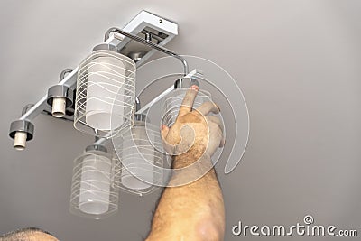 man unscrew glass shades from the chandelier Stock Photo
