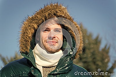 Man unshaven wear warm jacket with fur snowy nature background. Guy wear winter jacket with furry hood. Hipster winter Stock Photo