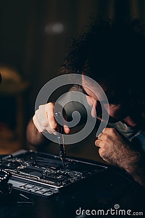 Man upgrading or repairing the laptop computer. Dark photo. Stock Photo