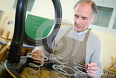 Man upholstering chair in workshop measure wooden board Stock Photo