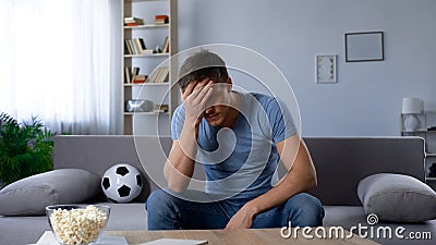 Man upset about defeat of football team, watching tv broadcast, unhappy fan Stock Photo