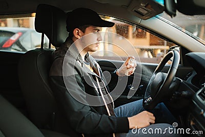 Man use disinfector in car. Handsome man protect himself and clean car inside using antiseptic Stock Photo