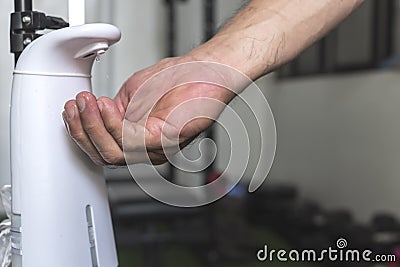 A man uses an automated hand sanitizer prior to entering a small gym Stock Photo