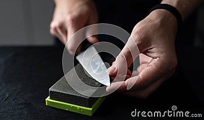 Man Sharpens Large Kitchen Knife With Natural Whetstone Stock Photo