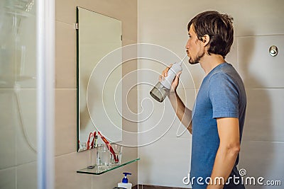 A man uses an oral irrigator in his bathroom Stock Photo