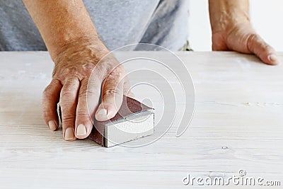 Man uses a sandpaper to restore wooden surface Stock Photo