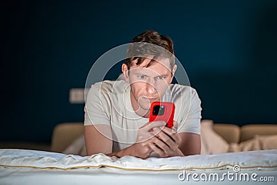 Man uses smartphone lying on bed. Online internet purchases solving business problems conducts chat Stock Photo