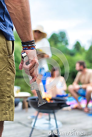 Man using bellows for preparing food in barbecue grill with friends on pier Stock Photo