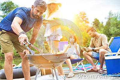 Man using bellows for preparing food in barbecue grill with friends on pier Stock Photo