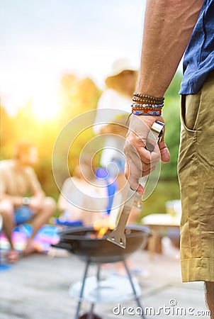 Man using bellows for preparing food in barbecue grill with friends on pier Stock Photo