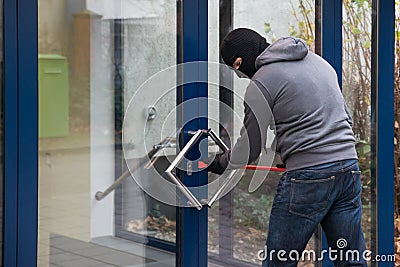 Man Using Crowbar To Open Glass Door Stock Photo