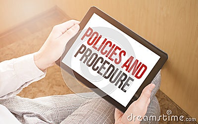 Man using digital tablet, close-up, coffee and keyboard on the background. Text Policies and Procedure Stock Photo