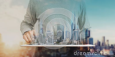 A man using digital tablet, and modern buildings hologram. Real estate business and building technology concept Stock Photo