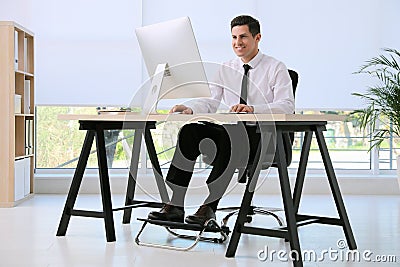 Man using footrest while working on computer Stock Photo